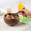 Coconut Shell Bowl with Wooden Spoon Hand holding a wooden spoon over a coconut shell bowl filled with yogurt, granola and berries